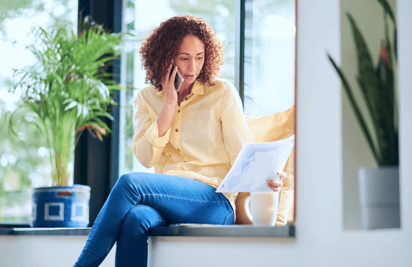 a woman talking on the phone while looking at some papers