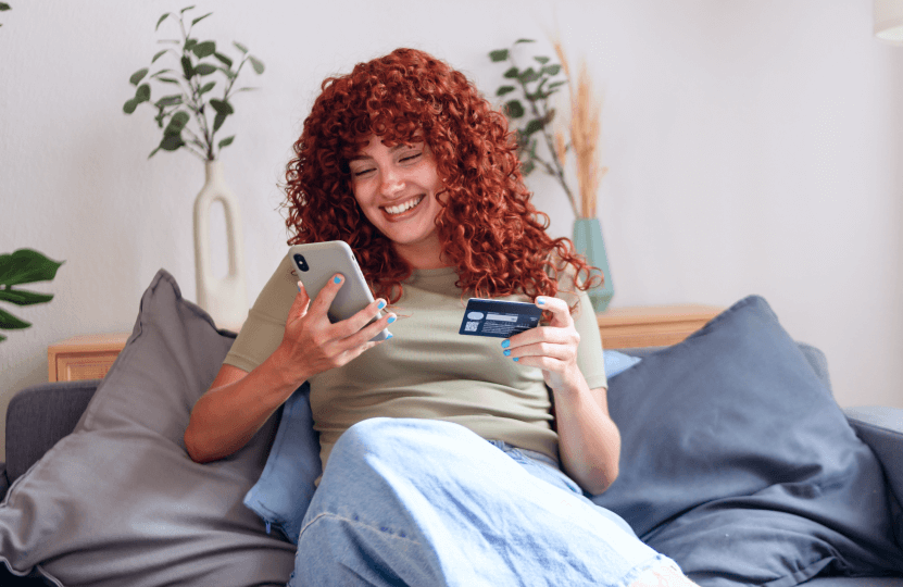 Woman smiling at her phone holding a credit card